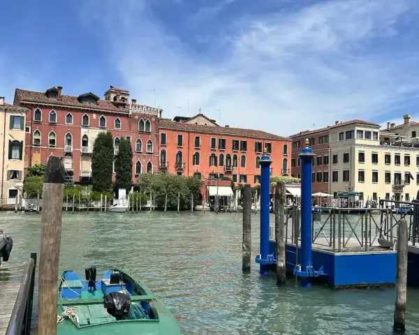 Canale di Venezia con edifici colorati e pontili blu. Per sapere how to get from Venice train station to San Marco, prendi un vaporetto.