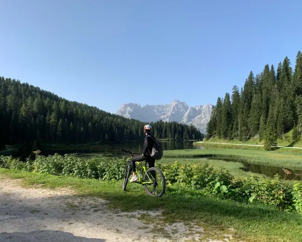 Ciclista ammira il panorama sul lago e le montagne lungo la ciclabile Auronzo Misurina.