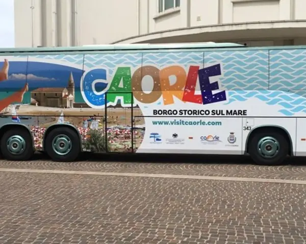 Bus turistico con grafica promozionale di Caorle, borgo storico sul mare. Immagini di spiaggia, mare e una donna in bikini.