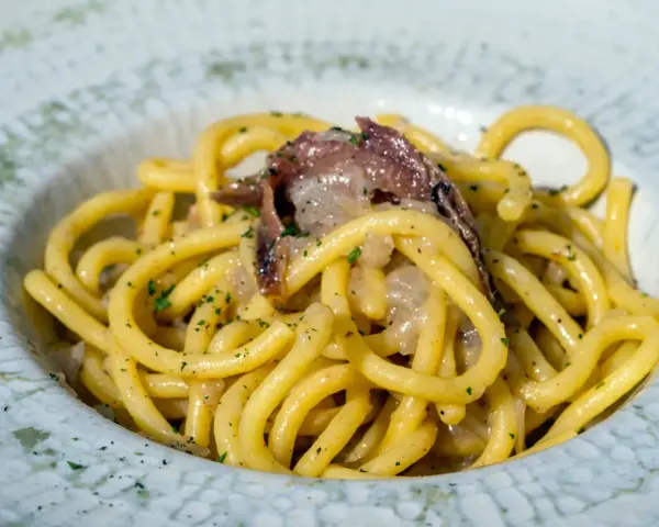 Spaghetti con acciughe e prezzemolo, un assaggio di cosa si mangia a Venezia. Un piatto semplice ma gustoso, perfetto per un pranzo veloce.