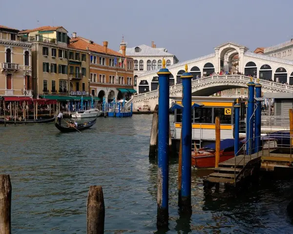 Gondola scivola sul Canal Grande, con il Ponte di Rialto e il vivace mercato di Rialto sullo sfondo.