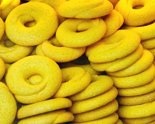 Una pila di dolcetti veneziani gialli, a forma di ciambella, con una texture leggermente ruvida.