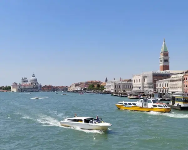 Venezia: il Canal Grande con la linea 1 vaporetto venezia fermate, barche e palazzi storici sotto un cielo azzurro.