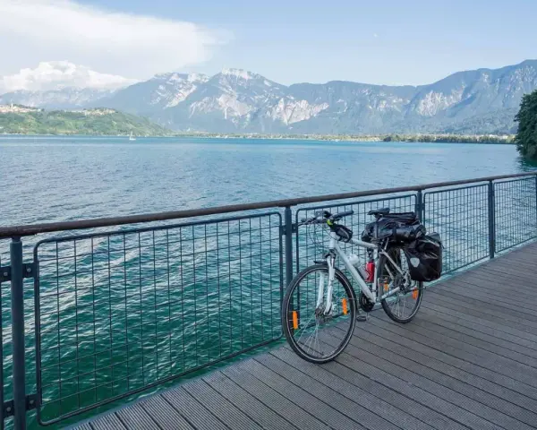 Bicicletta da turismo pronta per esplorare le ciclabili Dolomiti, con un lago azzurro e montagne maestose sullo sfondo.
