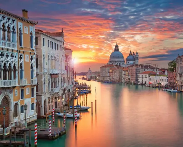 Tramonto sul Canal Grande, un quadro perfetto di posti romantici a Venezia. Palazzi storici e la Basilica di Santa Maria della Salute riflettono i colori del cielo.