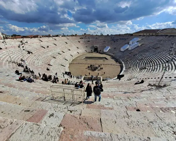 L'**arena di Verona colosseo** romano, con le sue gradinate affollate di turisti, sotto un cielo azzurro e nuvoloso.