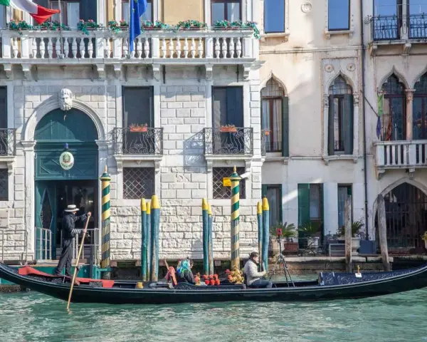 Gondola con gondoliere e passeggeri naviga lungo un canale a Venezia. Esplorare Venezia a piedi è un'esperienza, ma una gondola offre una prospettiva unica.