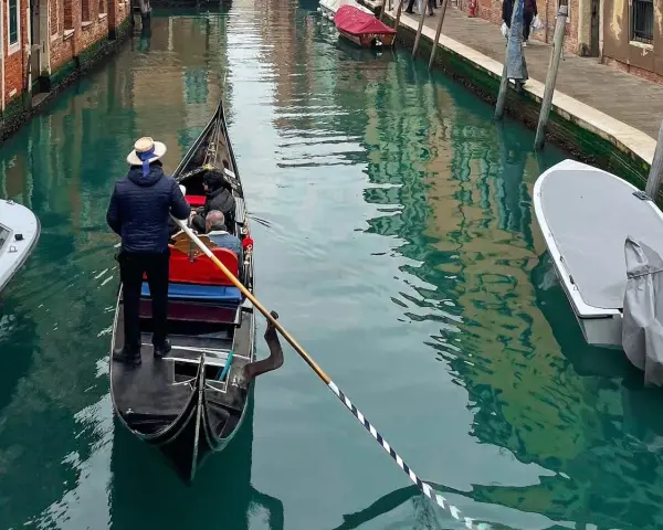 Gondola con gondoliere e passeggeri naviga in un canale veneziano vicino al park sant'andrea venezia.