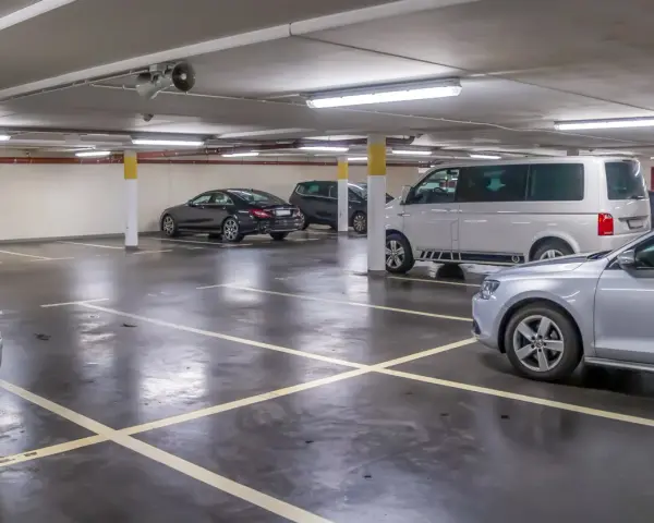 Parcheggio sotterraneo con diverse auto, tra cui un furgone bianco e una berlina nera. Un'auto argentata è in primo piano. Questo è l'ingresso a Venezia per chi arriva in auto.