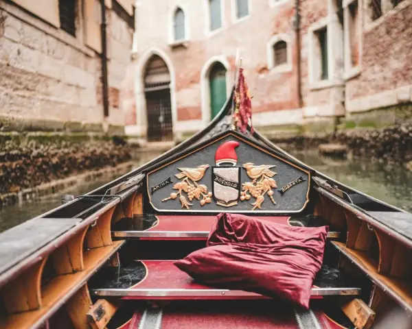 Gondola con cuscino rosso, pronta per un giro romantico a Venezia, città dell'amore.