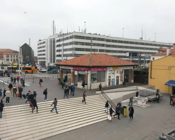Persone attraversano le scale a Piazzale Roma, vicino a una fermata del vaporetto.