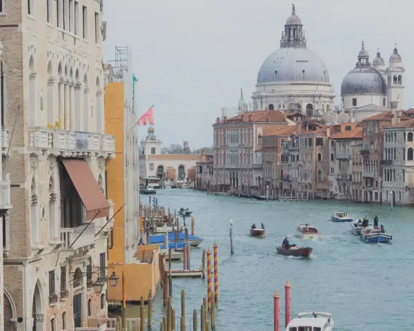 Canale di Venezia con barche, palazzi storici e la Basilica di Santa Maria della Salute. Il **costo entrata Venezia** è un tema attuale per i turisti.