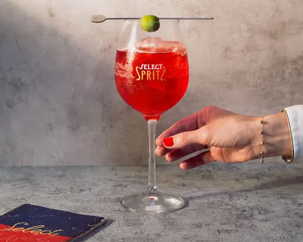 Un bicchiere di Spritz Select, con oliva e ghiaccio, pronto per essere gustato. Un tocco di Venezia in ogni sorso.
