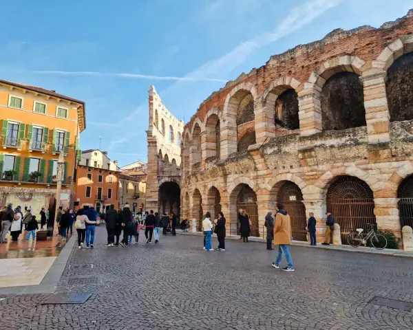 L'arena di Verona interno, con la sua maestosa struttura in pietra e archi, fa da sfondo a una piazza animata da turisti.