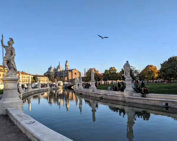 Statue e canale a Padova, con la Basilica di Sant'Antonio sullo sfondo. Ideale per capire quanti giorni per visitare Padova.