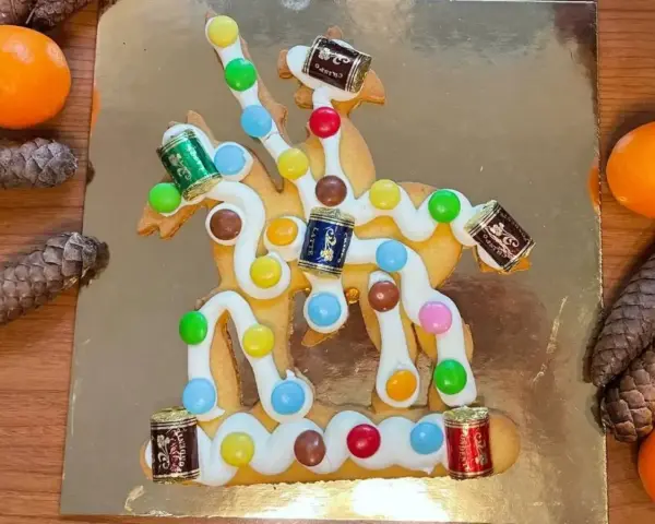 San Martino, dolce veneziano: biscotto decorato con glassa bianca, caramelle colorate e piccoli cioccolatini a forma di botte, su sfondo dorato.