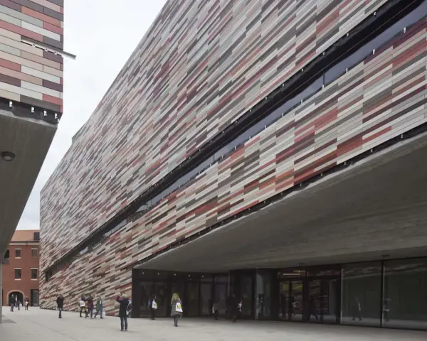 Il museo M9 a Mestre, con la sua facciata a listelli colorati, accoglie visitatori sotto un'imponente pensilina in cemento.