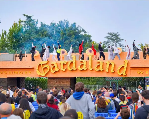 L'emozione di arrivare da Verona a Gardaland: artisti danzano sull'ingresso mentre la folla attende l'avventura.