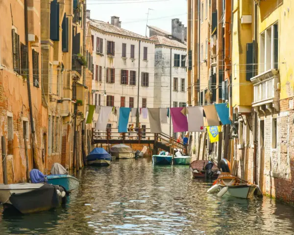 Angoli nascosti di Venezia: un canale tranquillo con barche ormeggiate e panni stesi ad asciugare tra case colorate.