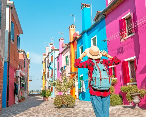 Una turista ammira le case colorate di Burano, un'isola raggiungibile con i traghetti da Chioggia.