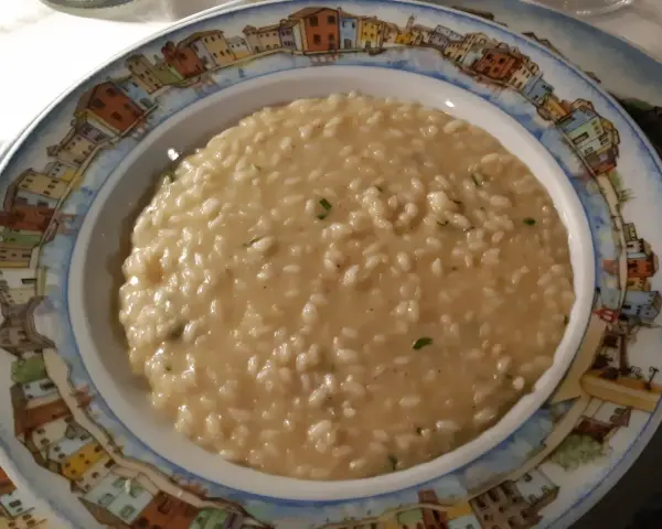 Un cremoso risotto di go Burano, servito in un piatto decorato con le case colorate dell'isola.