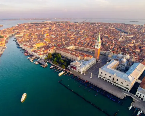 Vista aerea di Venezia al tramonto, con la Basilica di San Marco e il Palazzo Ducale che dominano la scena.