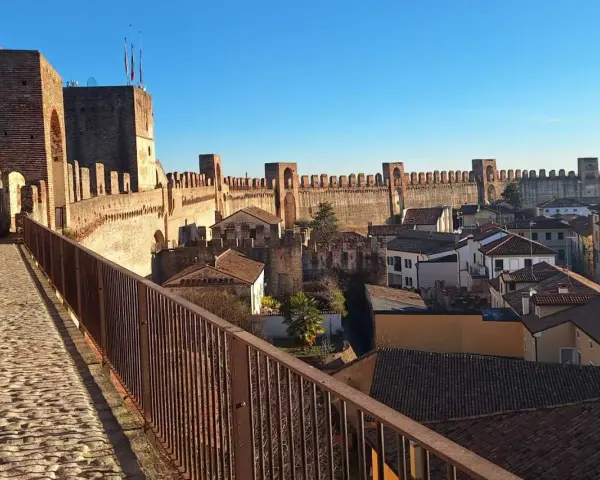 Passeggiata sulle mura della **cittadella** di Padova, con vista sui tetti e le torri medievali sotto un cielo azzurro.
