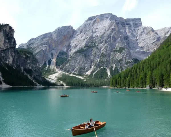 Lago turchese con barche a remi e maestose montagne veneto sullo sfondo.