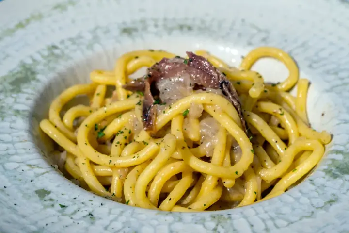 Spaghetti con acciughe e prezzemolo, un assaggio di cosa si mangia a Venezia. Un piatto semplice ma gustoso, perfetto per un pranzo veloce.