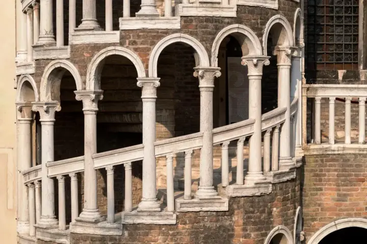 La scala Contarini a Venezia, con i suoi archi e colonne in marmo bianco, si snoda su una struttura in mattoni rossi, un'elegante spirale nel tempo.