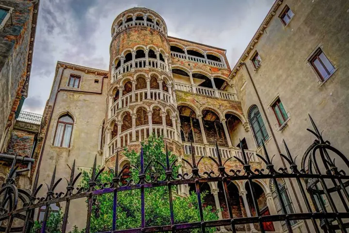 La scala chiocciola di Venezia, con i suoi archi e balconi, si erge maestosa tra antichi palazzi.