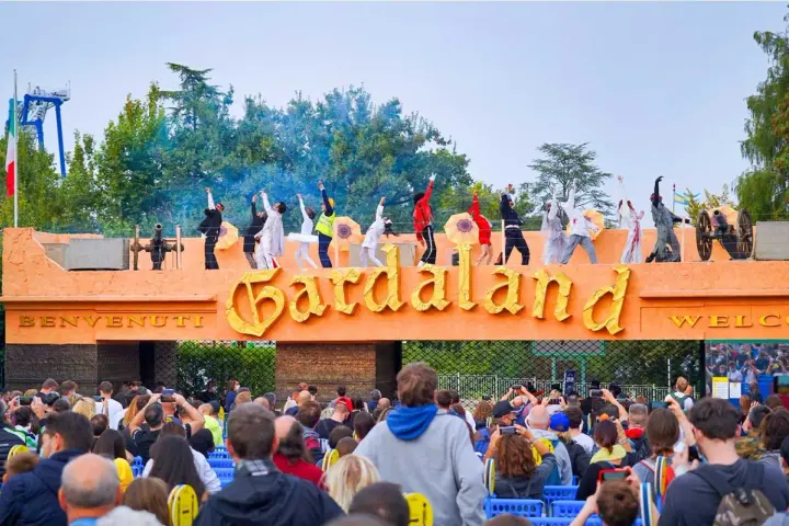 L'emozione di arrivare da Verona a Gardaland: artisti danzano sull'ingresso mentre la folla attende l'avventura.