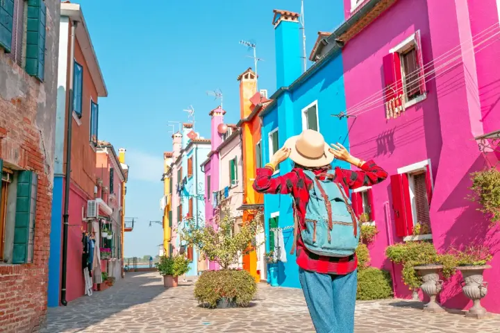 Una turista ammira le case colorate di Burano, un'isola raggiungibile con i traghetti da Chioggia.