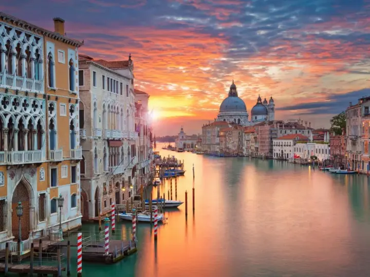 Tramonto sul Canal Grande, un quadro perfetto di posti romantici a Venezia. Palazzi storici e la Basilica di Santa Maria della Salute riflettono i colori del cielo.