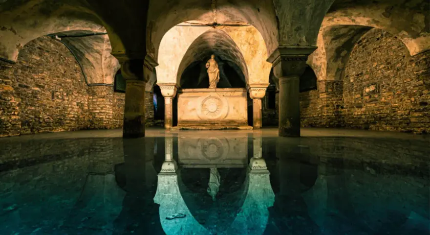 Sotterranei di Venezia misteriosa, con statue e riflessi sull'acqua.
