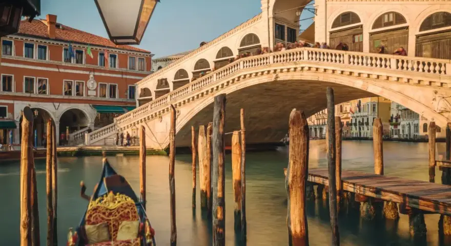 Gondola ferma in un canale di Venezia inverno, con il Ponte di Rialto sullo sfondo.