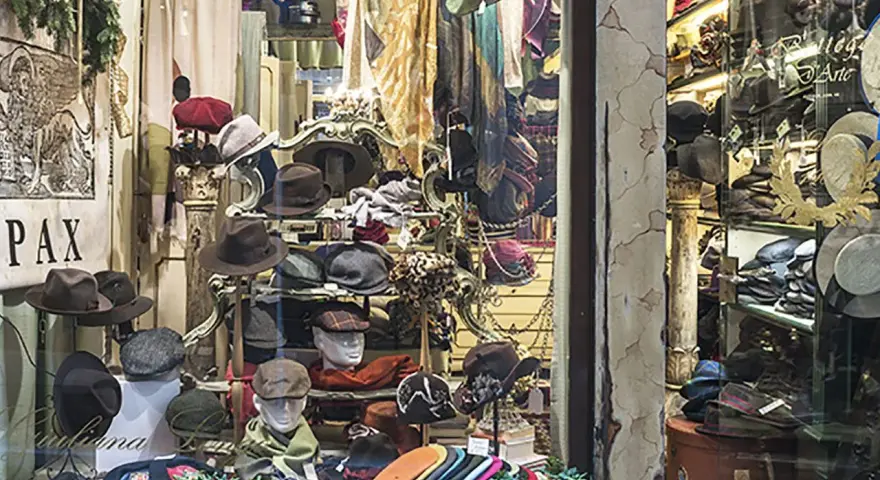 Vetrina di negozi Venezia con cappelli eleganti e sciarpe colorate, un'esplosione di stile per ogni occasione.