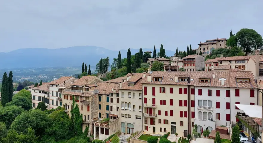 Asolo, cosa vedere: un borgo collinare con case in pietra, tetti rossi e giardini lussureggianti, incastonato tra le montagne.