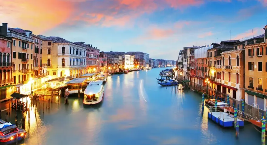 Il Canal Grande di Venezia, con le sue opere d'arte architettoniche illuminate al tramonto, accoglie gondole e vaporetti.