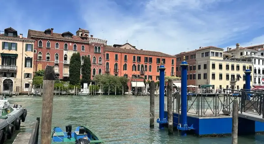 Canale di Venezia con edifici colorati e pontili blu. Per sapere how to get from Venice train station to San Marco, prendi un vaporetto.