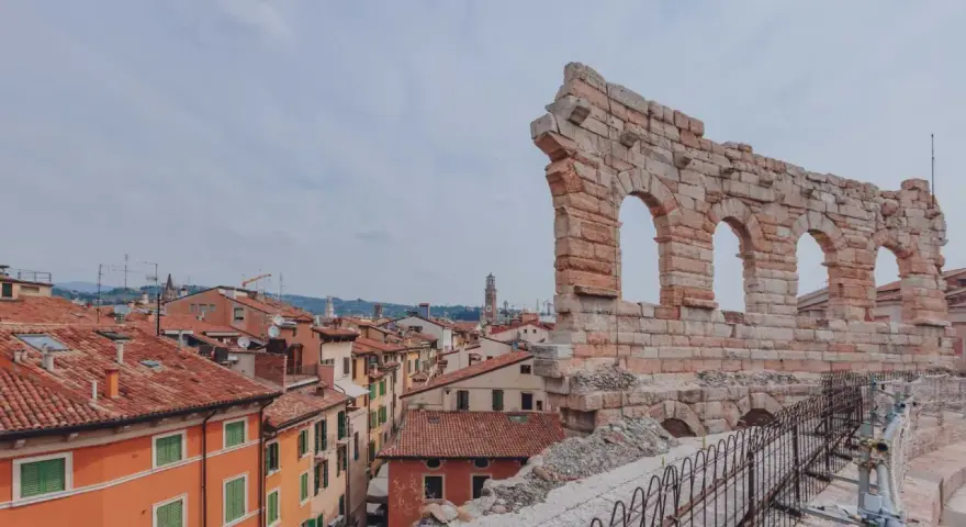 Resti antichi dell'Arena di Verona, testimoni di quanti anni ha l'Arena di Verona, si stagliano su un panorama di tetti rossi.