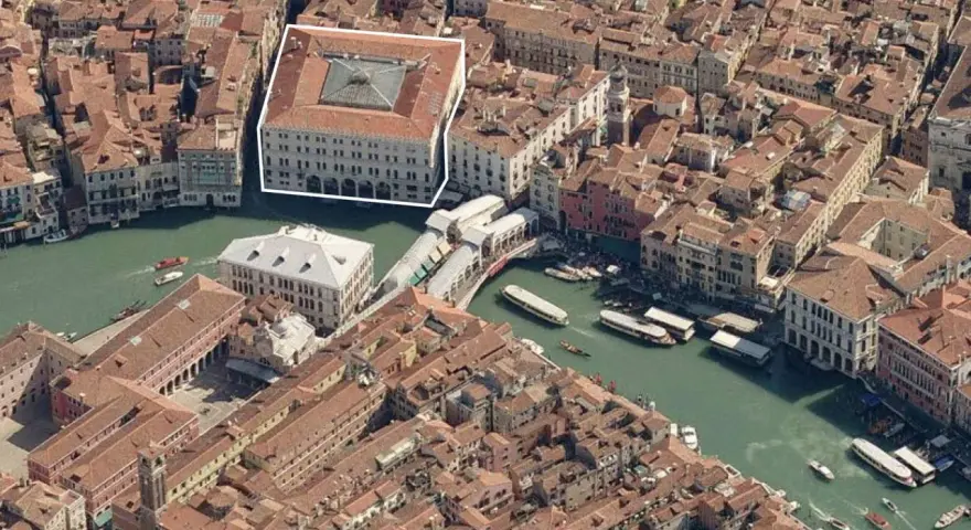 Vista aerea di Venezia, evidenziato il Fondaco dei Tedeschi, un imponente edificio storico affacciato sul Canal Grande, vicino al Ponte di Rialto.