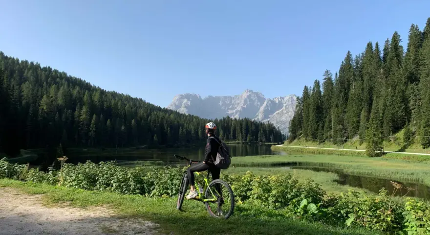 Ciclista ammira il panorama sul lago e le montagne lungo la ciclabile Auronzo Misurina.