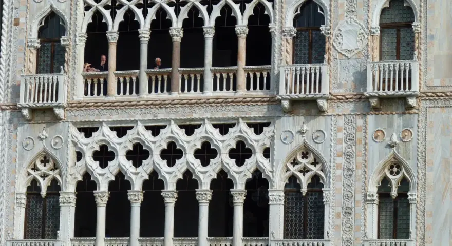 Dettaglio del **Palazzo Cadoro** con le sue finestre a trifora e balconi ornati. Persone osservano dal primo piano.
