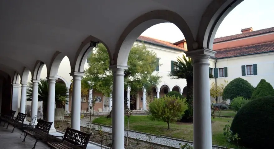 Portico con archi e colonne bianche, panchine e un giardino interno. Per sapere isola degli armeni come arrivare, visita questo luogo tranquillo.