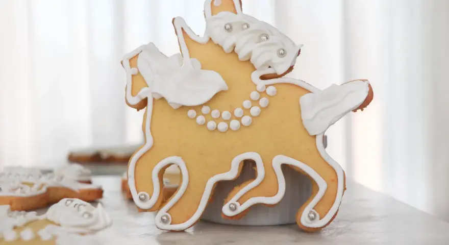 Biscotti a forma di cavallo decorati con glassa bianca e perline argentate, un dolce San Martino che racconta una storia.
