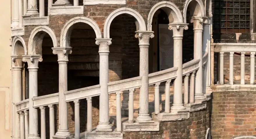 La scala Contarini a Venezia, con i suoi archi e colonne in marmo bianco, si snoda su una struttura in mattoni rossi, un'elegante spirale nel tempo.