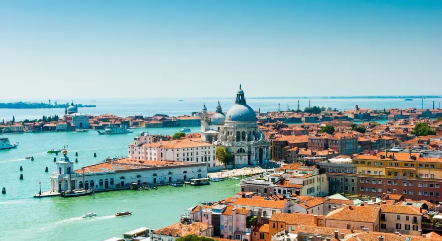Venezia, con la sua Basilica di Santa Maria della Salute e i canali vibranti, offre infinite curiosità. Le case colorate e i tetti rossi si specchiano sull'acqua.