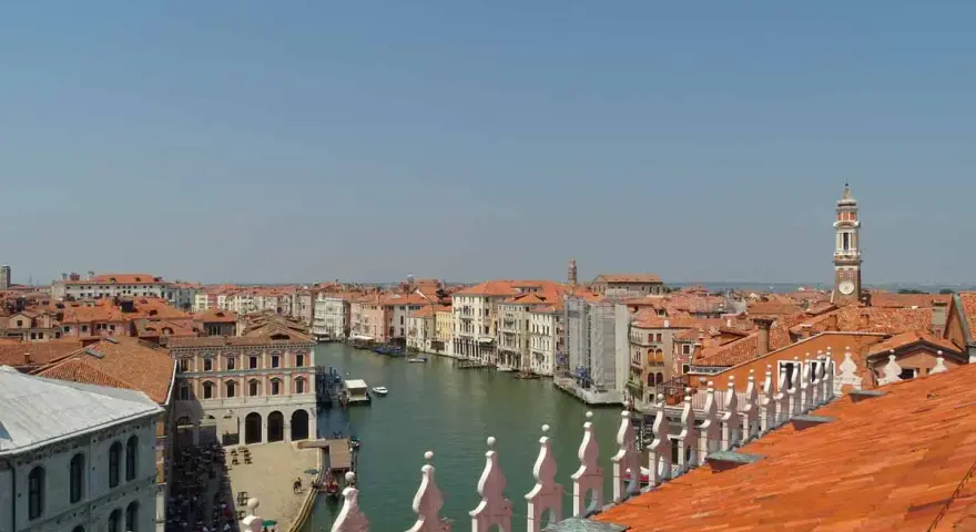 Vista dall'alto dei tetti rossi di Venezia, con il Canal Grande e le sue calli animate.