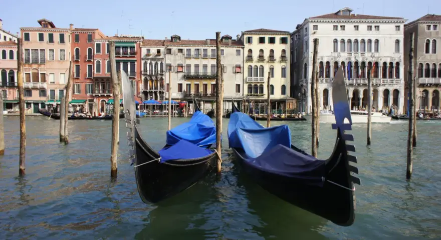 Gondole ormeggiate sul Canal Grande, pronte per le escursioni a Venezia. Edifici storici sullo sfondo.
